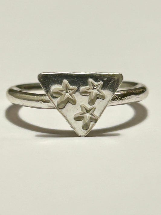 Silver ring with a triangular design featuring three stars on a light gray background